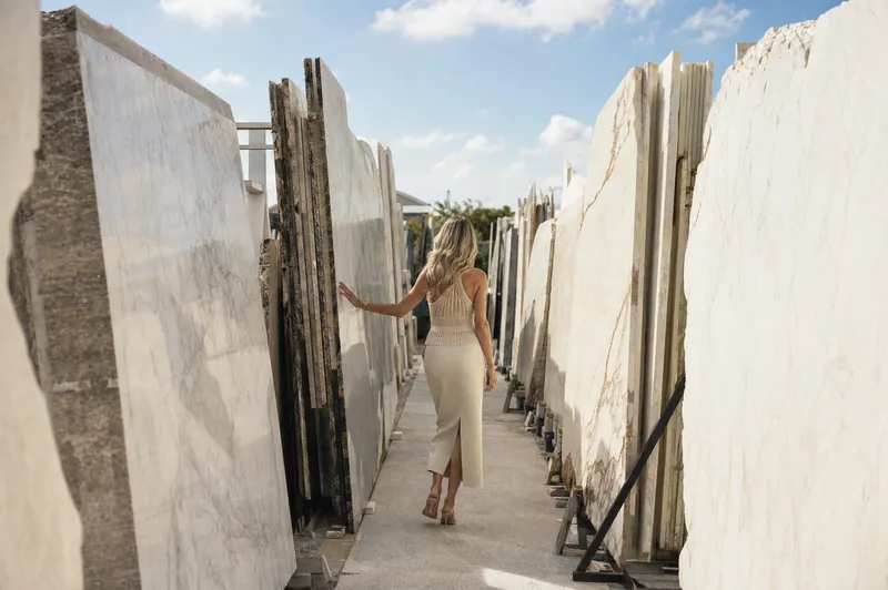 Jessica walking between marble slabs in a stone yard, choosing the stone for a kitchen